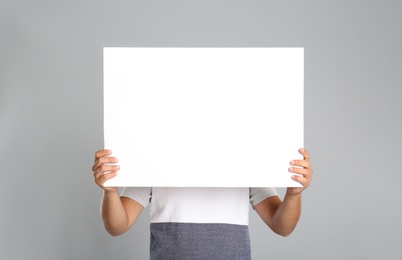 Photo of Man holding white blank poster on grey background. Mockup for design