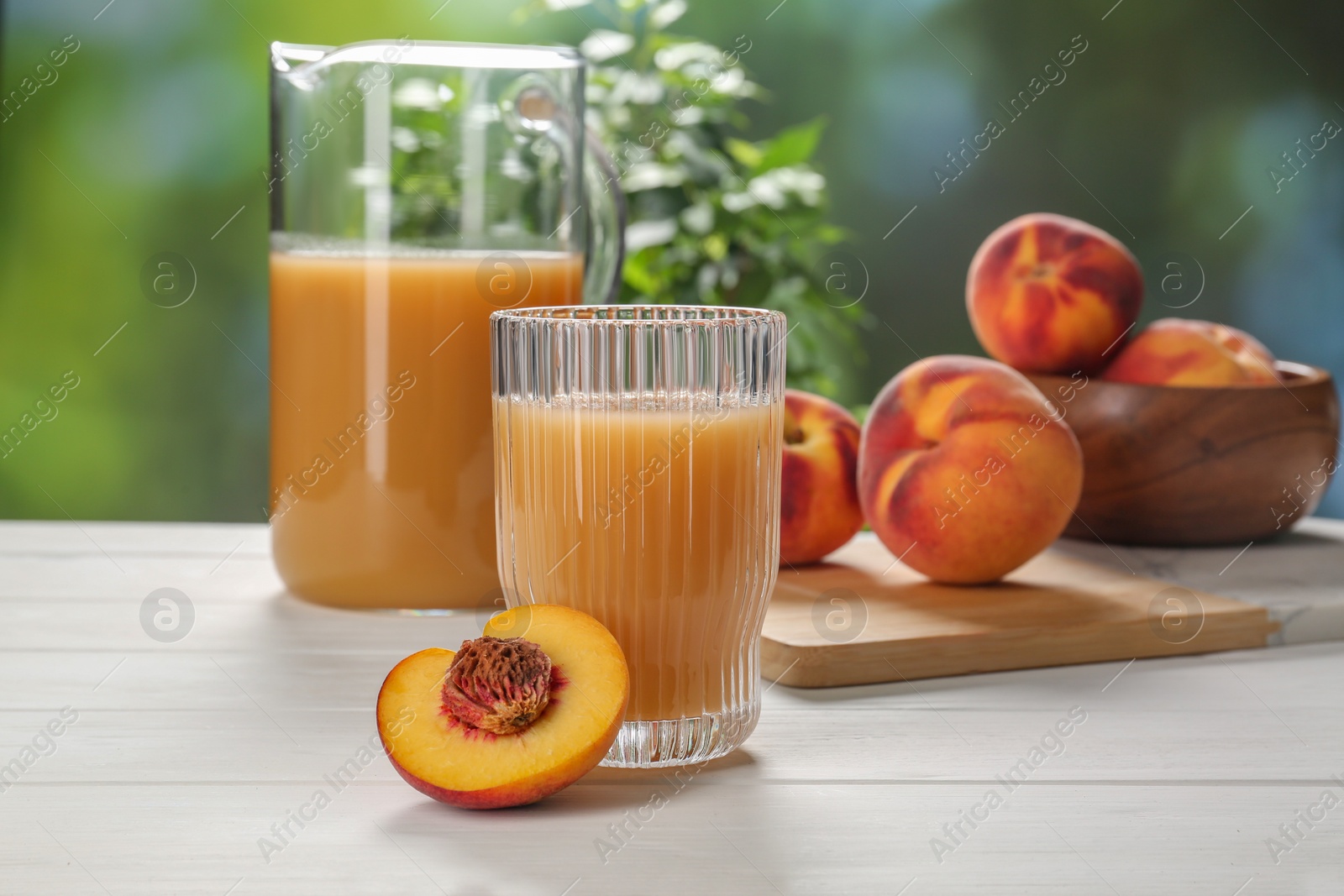 Photo of Delicious peach juice and fresh fruits on white wooden table