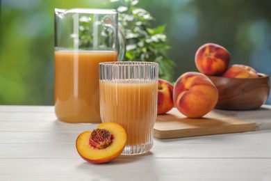 Delicious peach juice and fresh fruits on white wooden table