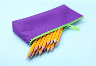 Photo of Many sharp pencils in pencil case on light blue background