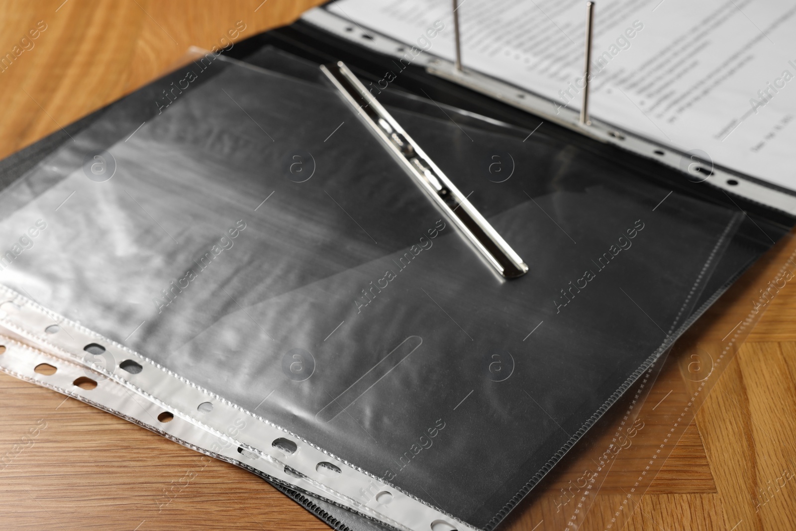 Photo of File folder with punched pockets on wooden table, closeup