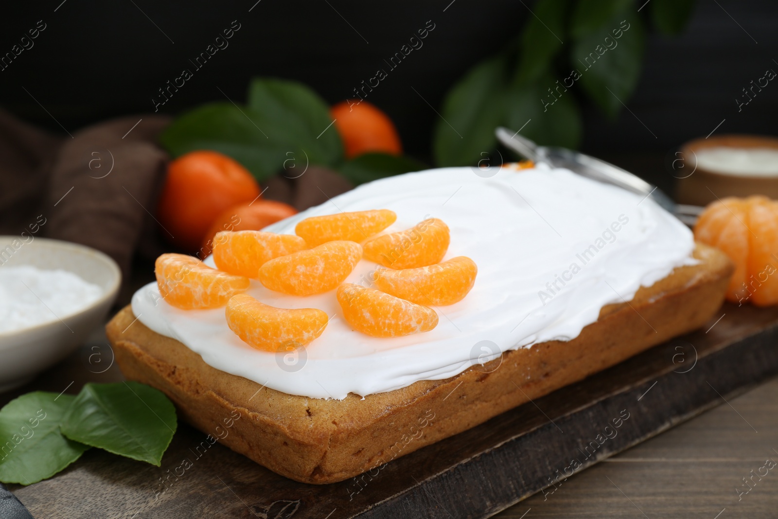 Photo of Delicious homemade yogurt cake with tangerines and cream on wooden table, closeup
