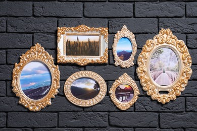 Vintage frames with photos of beautiful landscapes hanging on dark brick wall