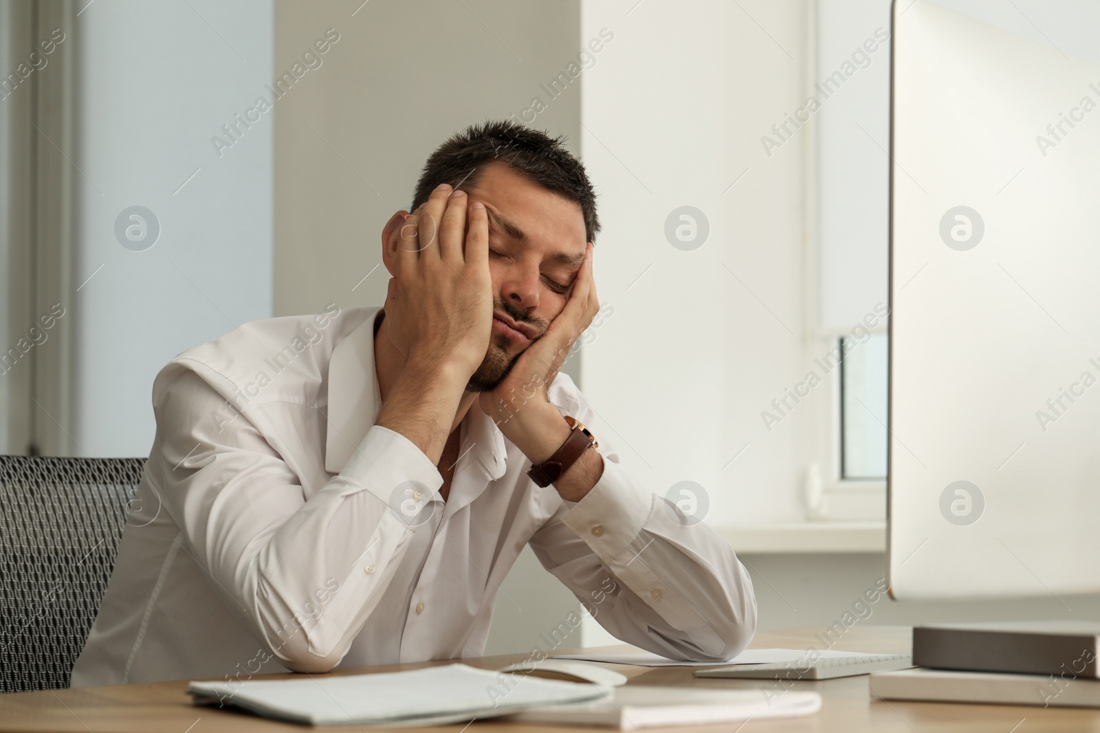 Photo of Sleepy man snoozing at workplace in office