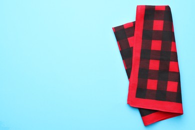 Photo of Folded red checkered bandana on light blue background, top view. Space for text