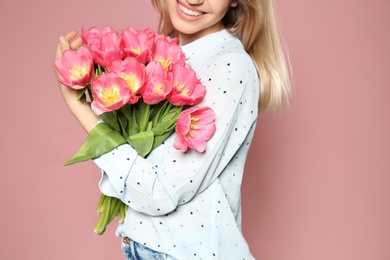 Beautiful girl with spring tulips on pink background, closeup. International Women's Day