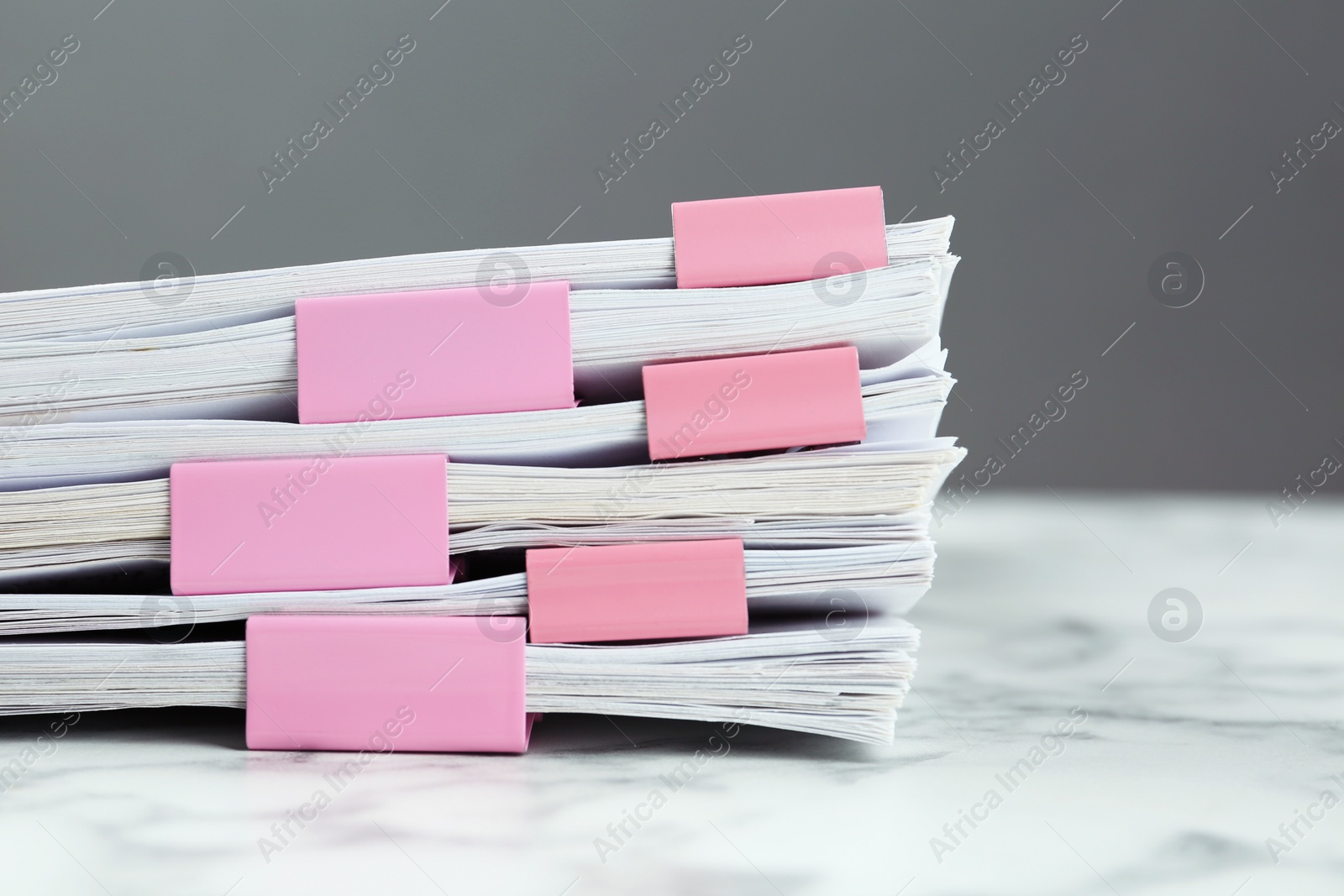 Photo of Stack of documents with binder clips on marble table, closeup