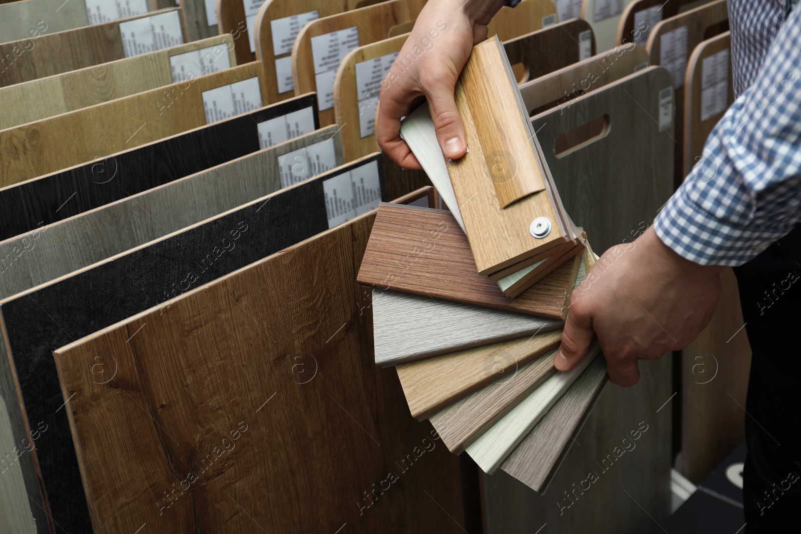 Photo of Man with samples of wooden flooring in shop, closeup