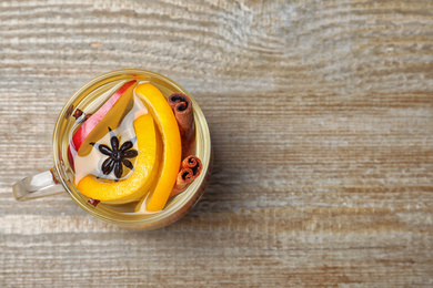 Photo of Aromatic mulled wine on wooden table, top view. Space for text