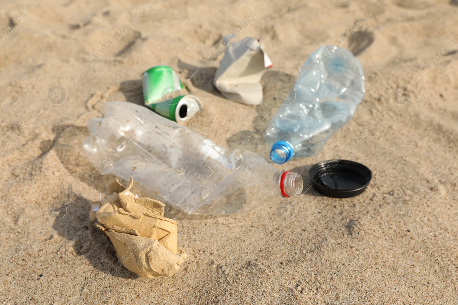 Photo of Garbage scattered on sand, closeup. Recycling problem