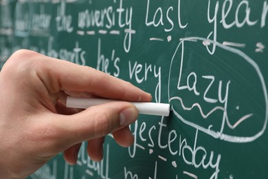 English teacher writing with chalk on green chalkboard, closeup