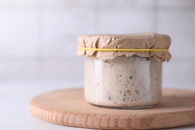 Sourdough starter in glass jar on table, closeup. Space for text