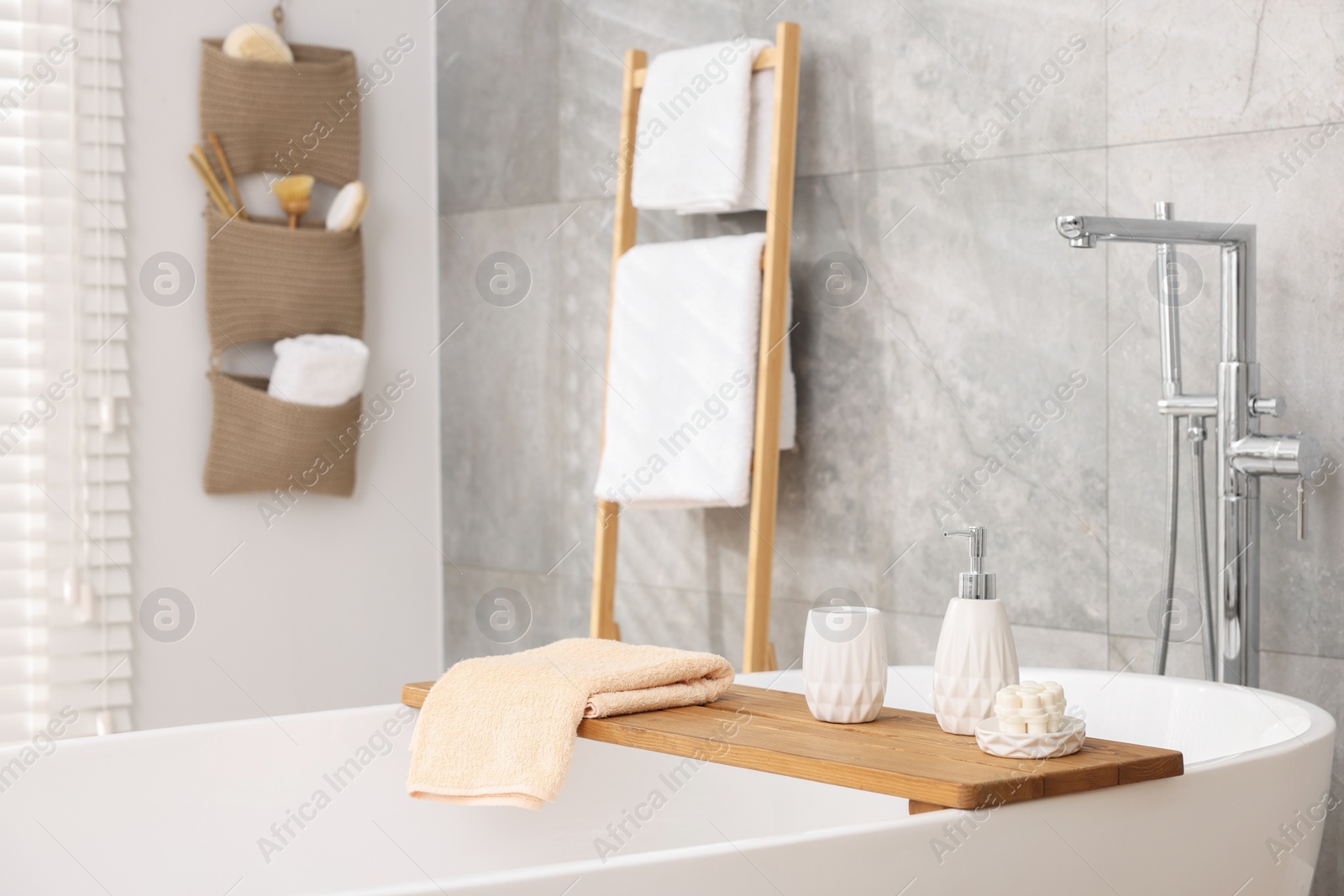 Photo of Set of different bath accessories and soap on tub in bathroom