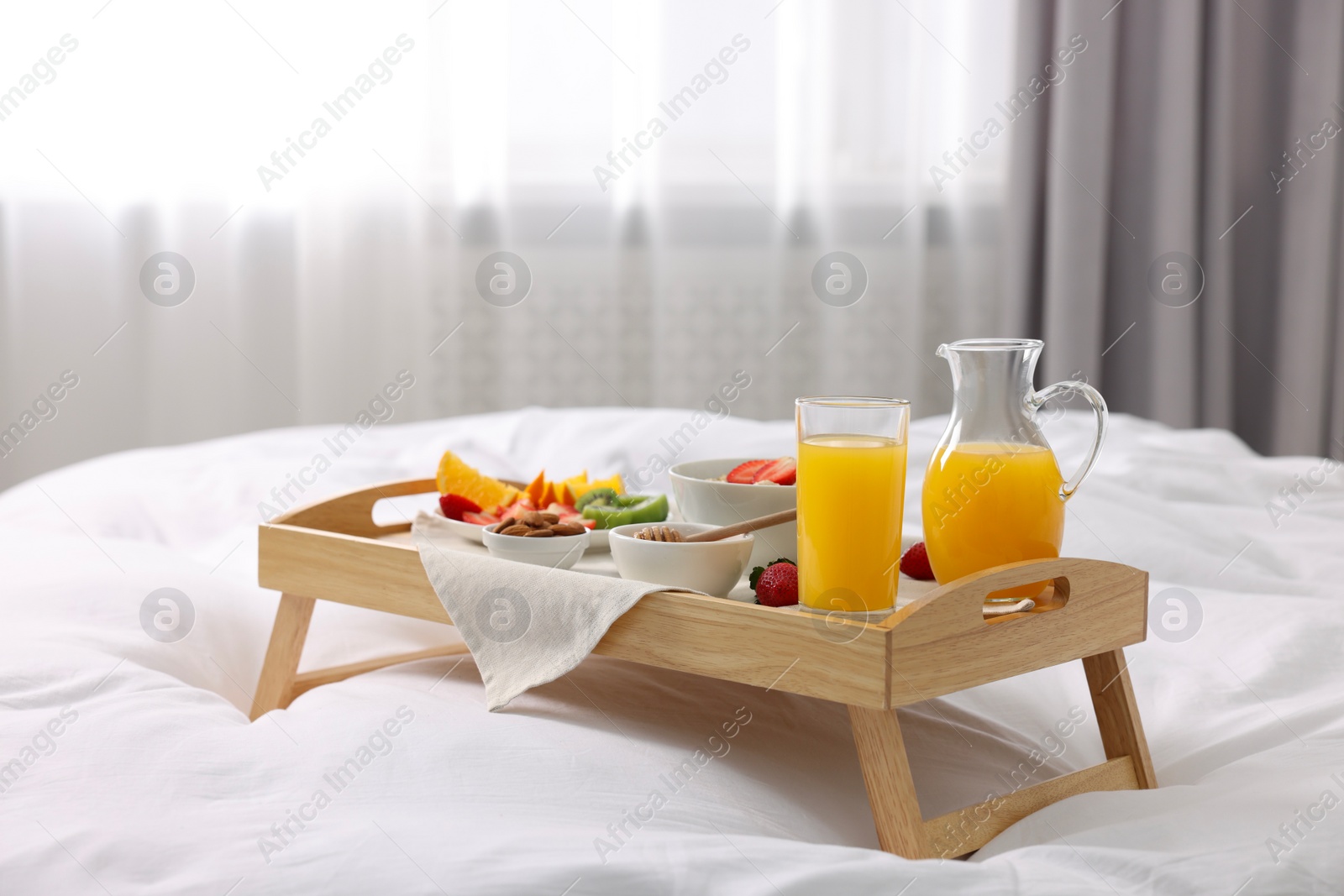 Wooden tray with tasty breakfast on bed at home Photo of Wooden tray with tasty breakfast on bed at home