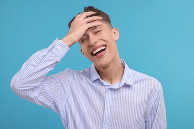 Young man laughing on light blue background