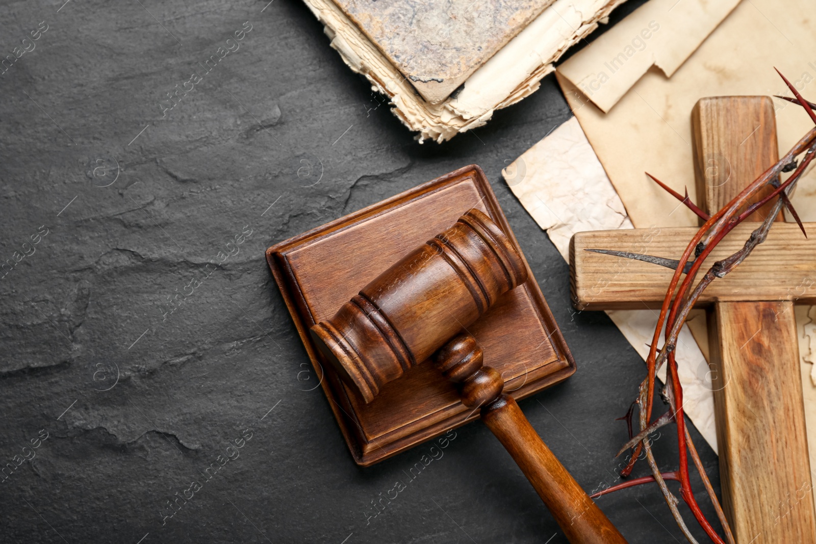 Photo of Judge gavel, wooden cross and crown of thorns on black table, flat lay. Space for text