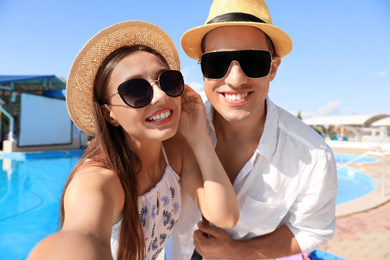 Happy couple taking selfie near swimming pool. Summer vacation