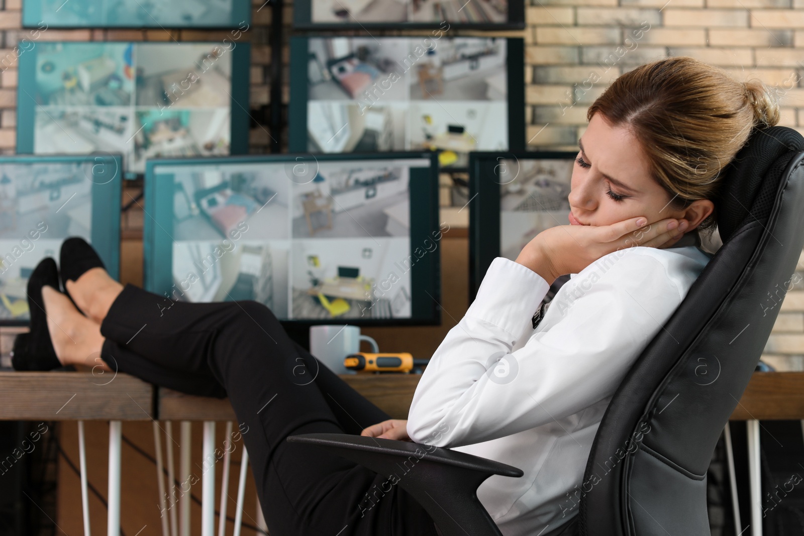 Photo of Female security guard sleeping at workplace. CCTV surveillance