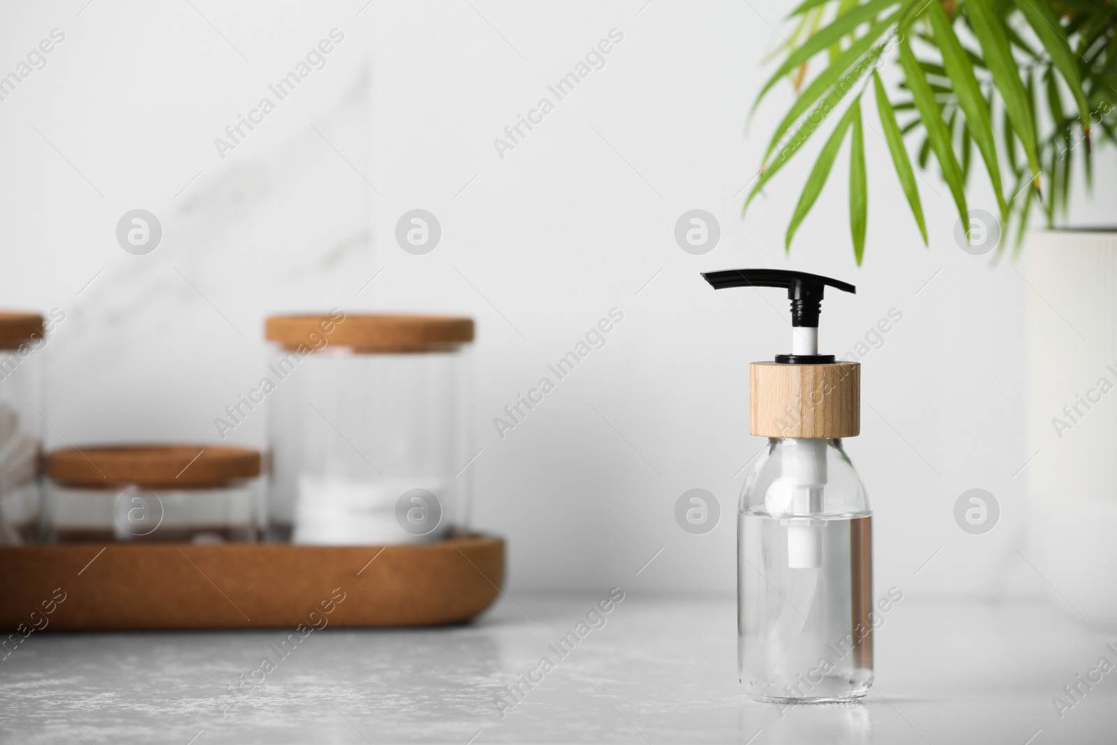 Photo of Bottle with dispenser cap on table. Space for text