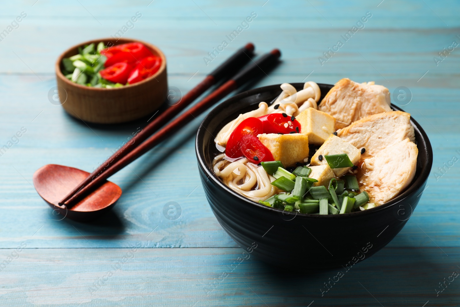 Photo of Delicious ramen served on light blue wooden table. Noodle soup