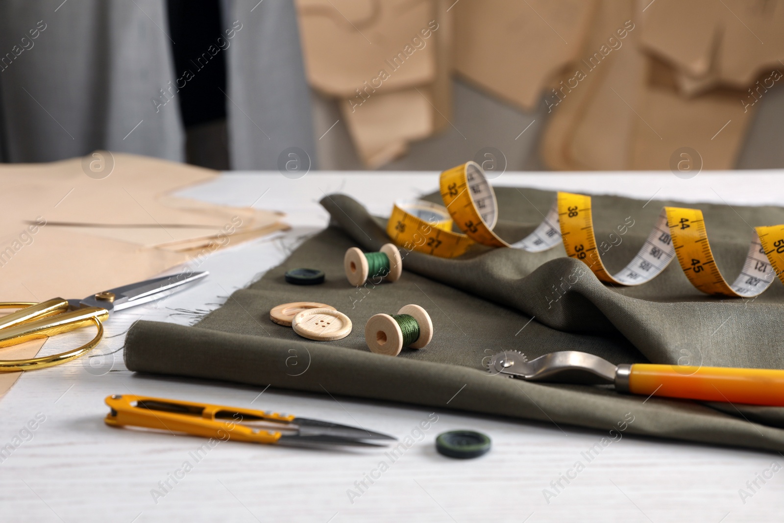 Photo of Set of sewing supplies and accessories with fabric on white wooden table indoors