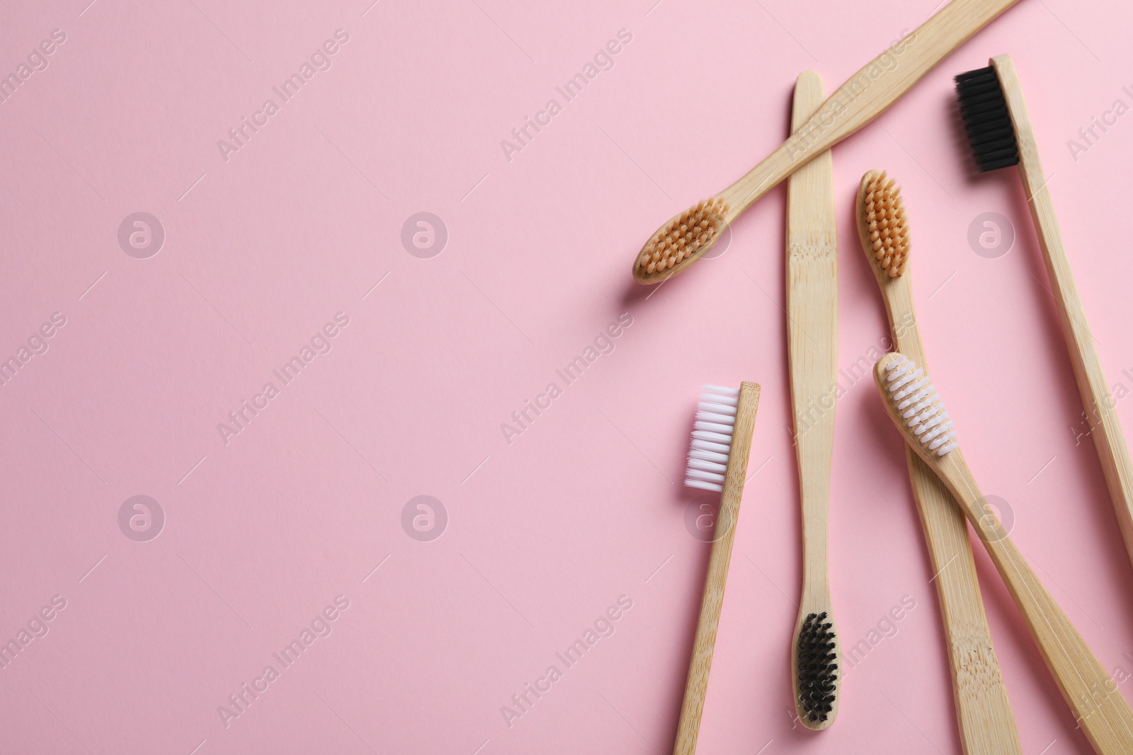 Photo of Bamboo toothbrushes on pink background, flat lay. Space for text