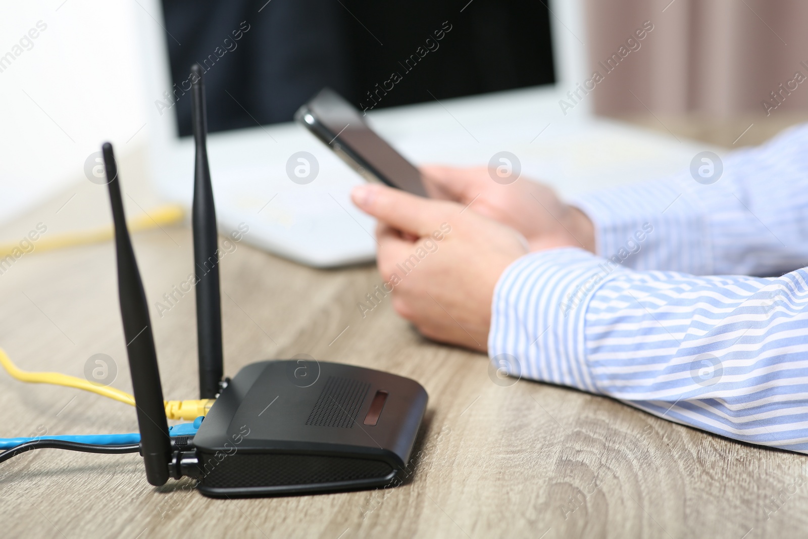 Photo of Woman with smartphone connecting to internet via Wi-Fi router at wooden table indoors, closeup