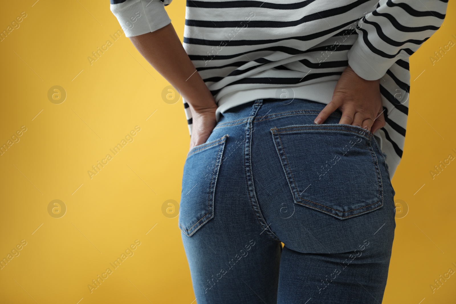 Photo of Woman wearing jeans on yellow background, closeup