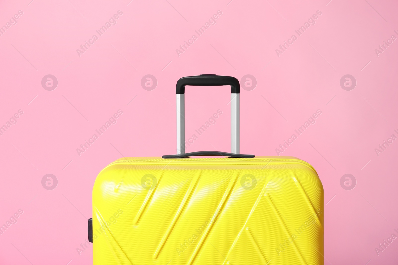 Photo of Modern yellow suitcase on light pink background