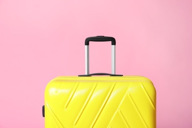 Photo of Modern yellow suitcase on light pink background