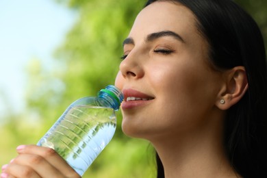 Photo of Young woman drinking water outdoors, closeup/ Refreshing drink