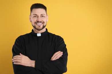 Priest wearing cassock with clerical collar on yellow background, space for text