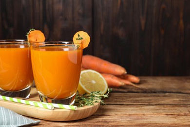 Photo of Glasses of tasty carrot juice and ingredients on wooden table, closeup. Space for text