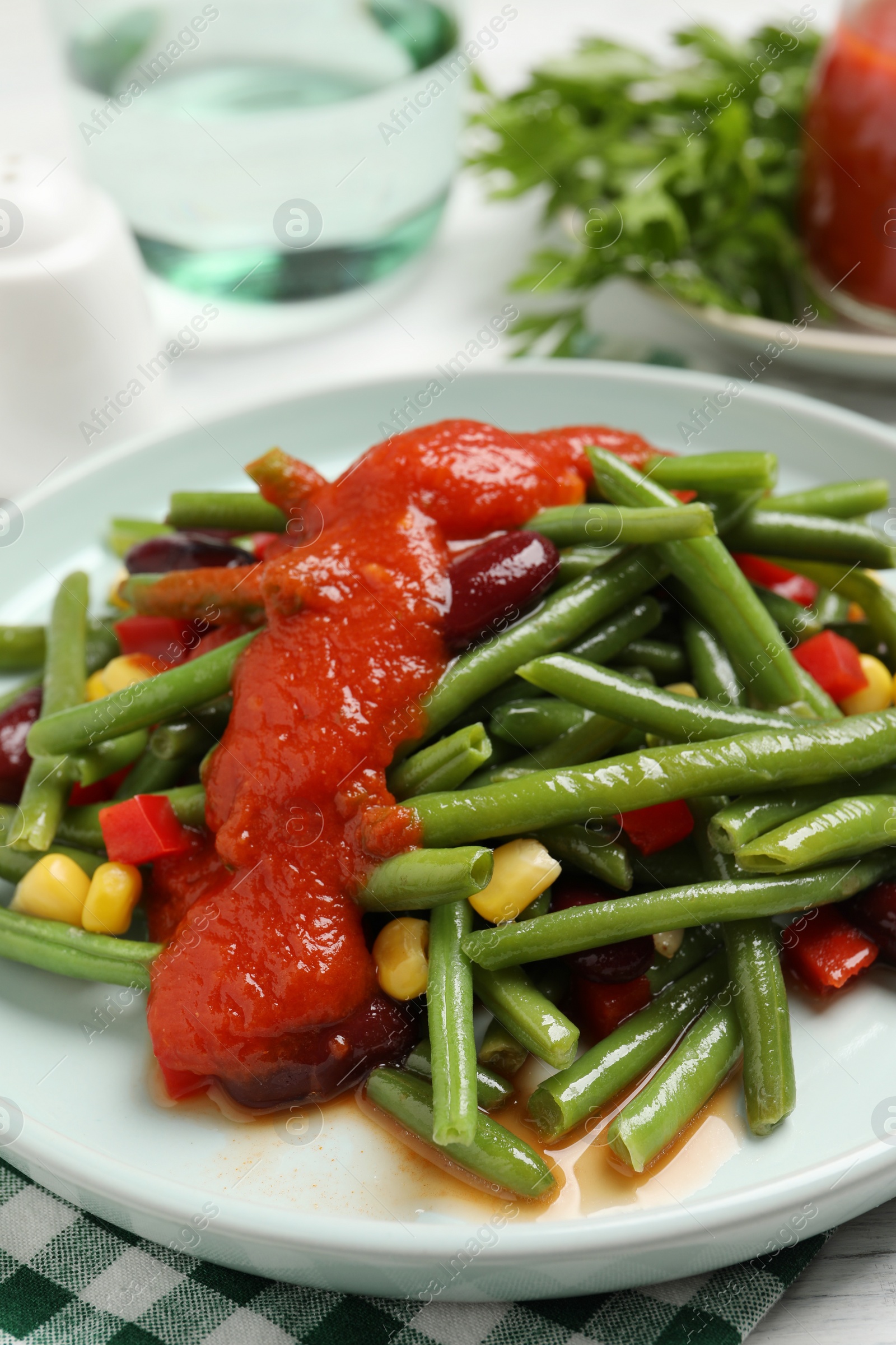 Photo of Delicious salad with green beans and tomato sauce served on table, closeup
