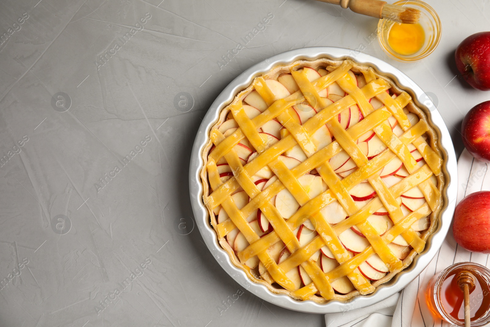 Photo of Raw traditional English apple pie in baking dish on light grey table, flat lay. Space for text