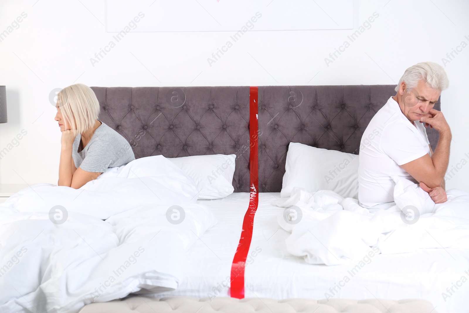 Photo of Upset mature couple with relationship problems sitting on bed at home