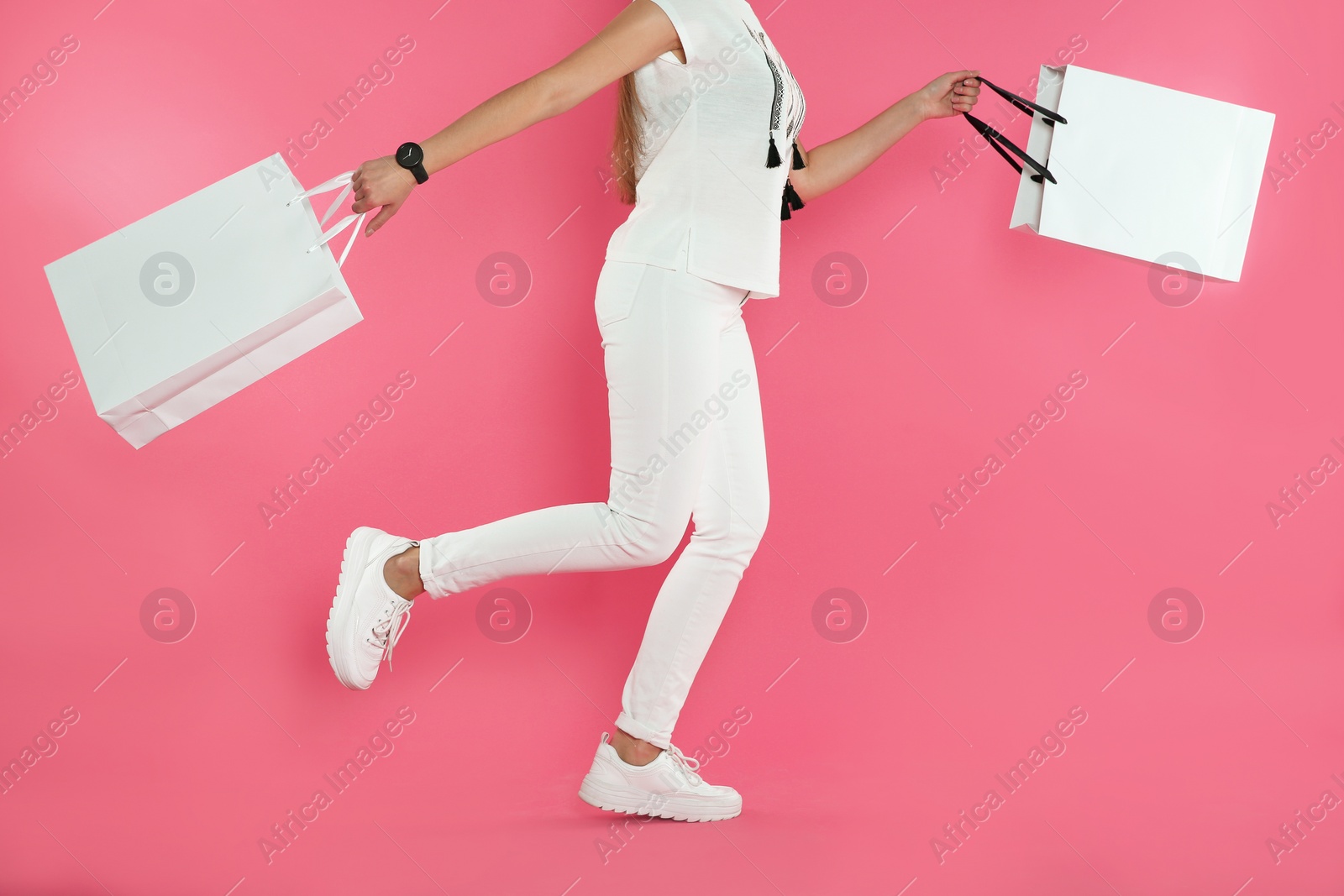 Photo of Woman running with paper shopping bags on color background. Mock up for design