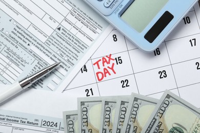 Photo of Calendar with date reminder about tax day, documents, money, pen and calculator, top view