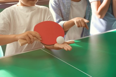 Photo of Little boy with friends playing ping pong indoors, closeup