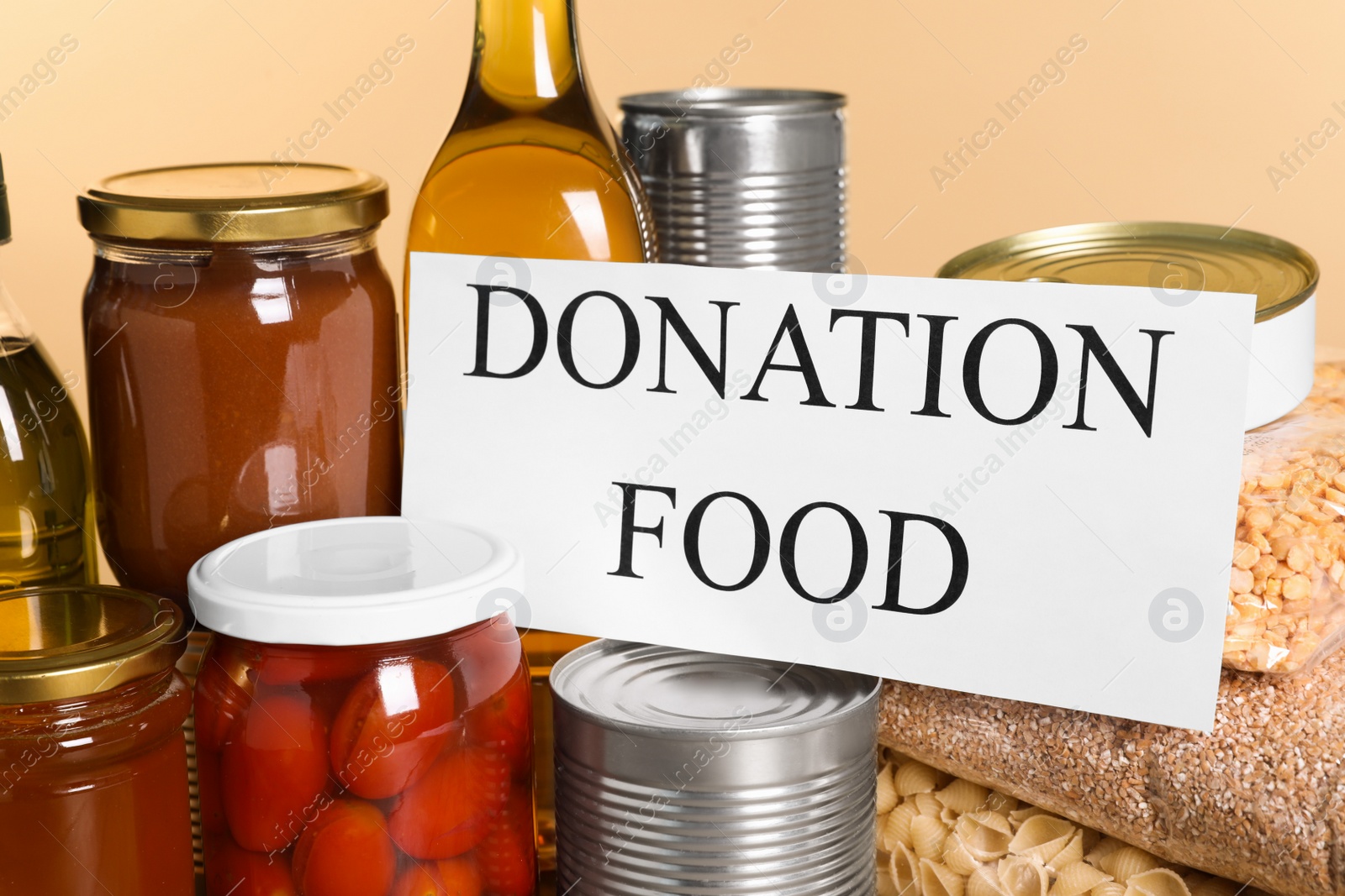 Photo of Card with words Donation Food and different products on beige background, closeup