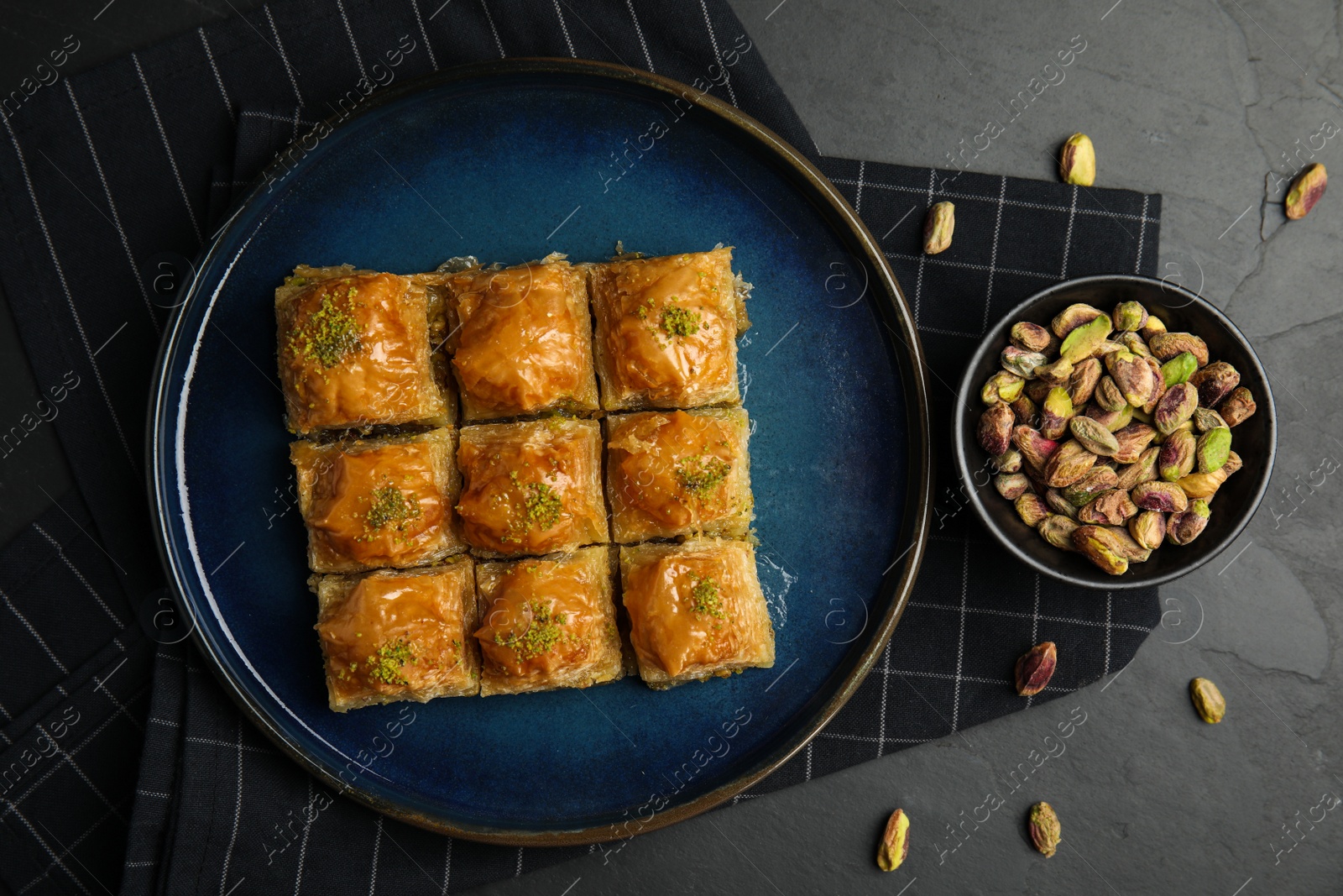 Photo of Delicious sweet baklava with pistachios on black table, flat lay