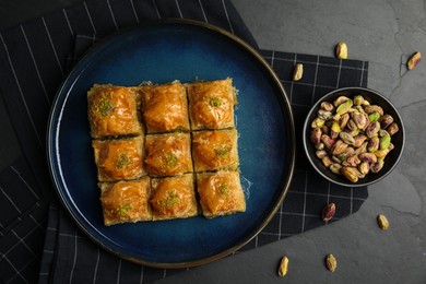 Photo of Delicious sweet baklava with pistachios on black table, flat lay