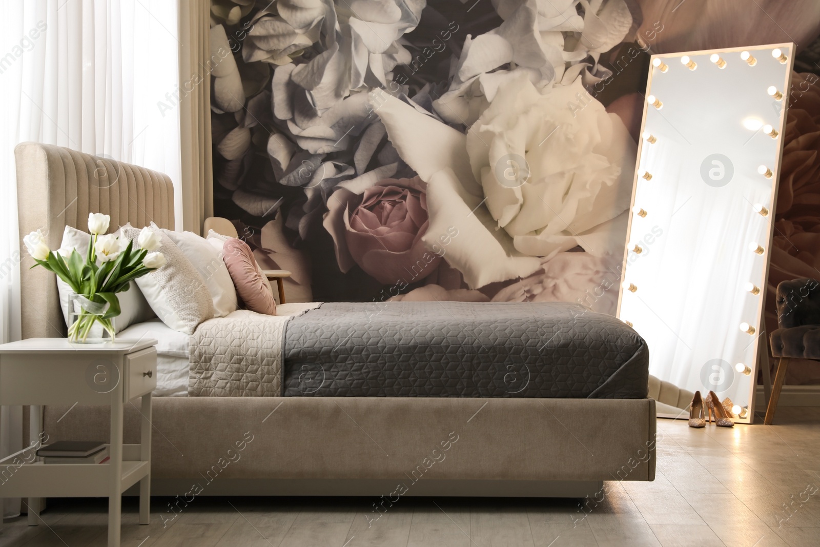 Photo of Beautiful room interior with large bed, mirror and floral pattern on wall