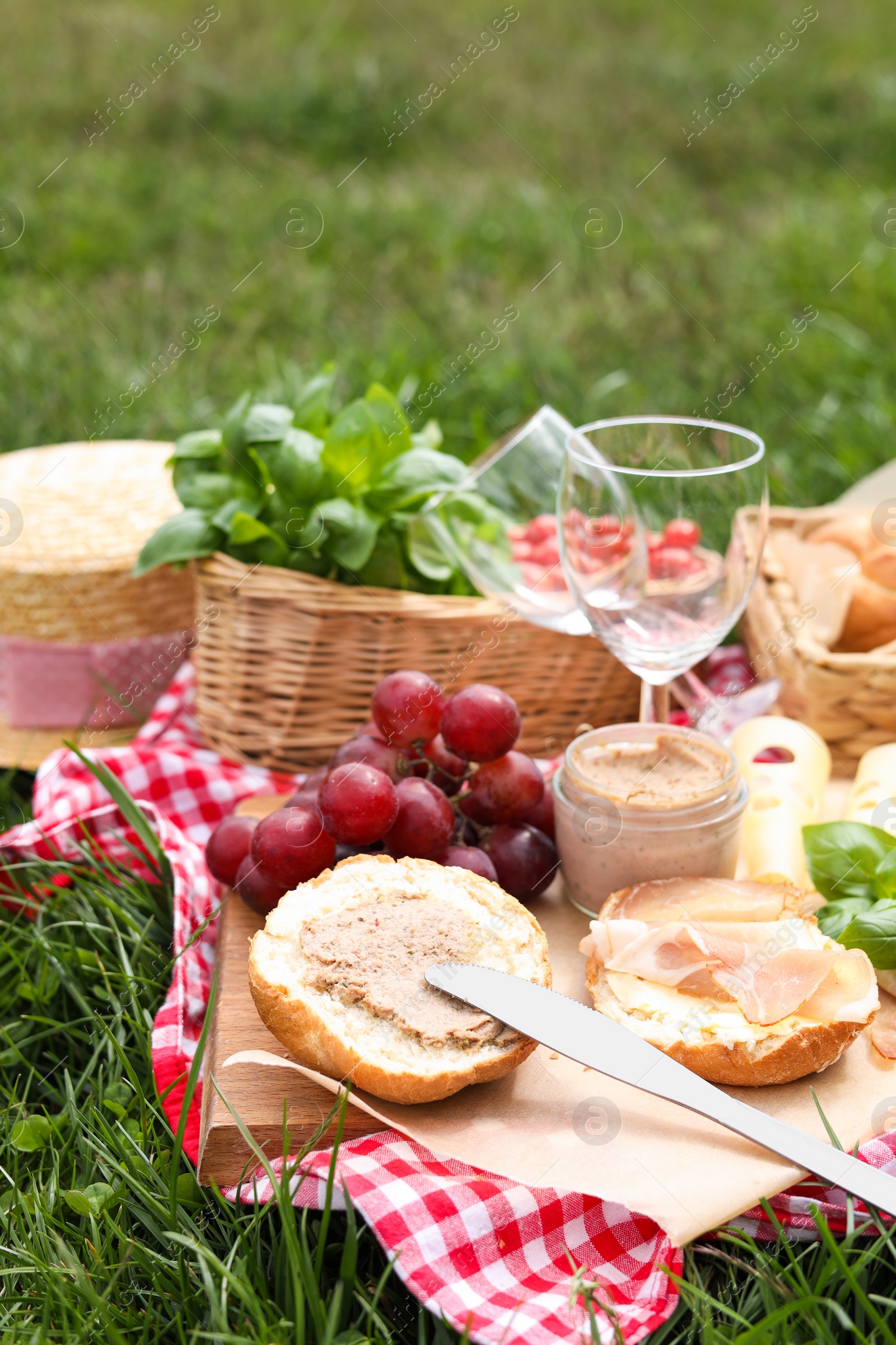 Photo of Picnic blanket with wineglasses and food on green grass