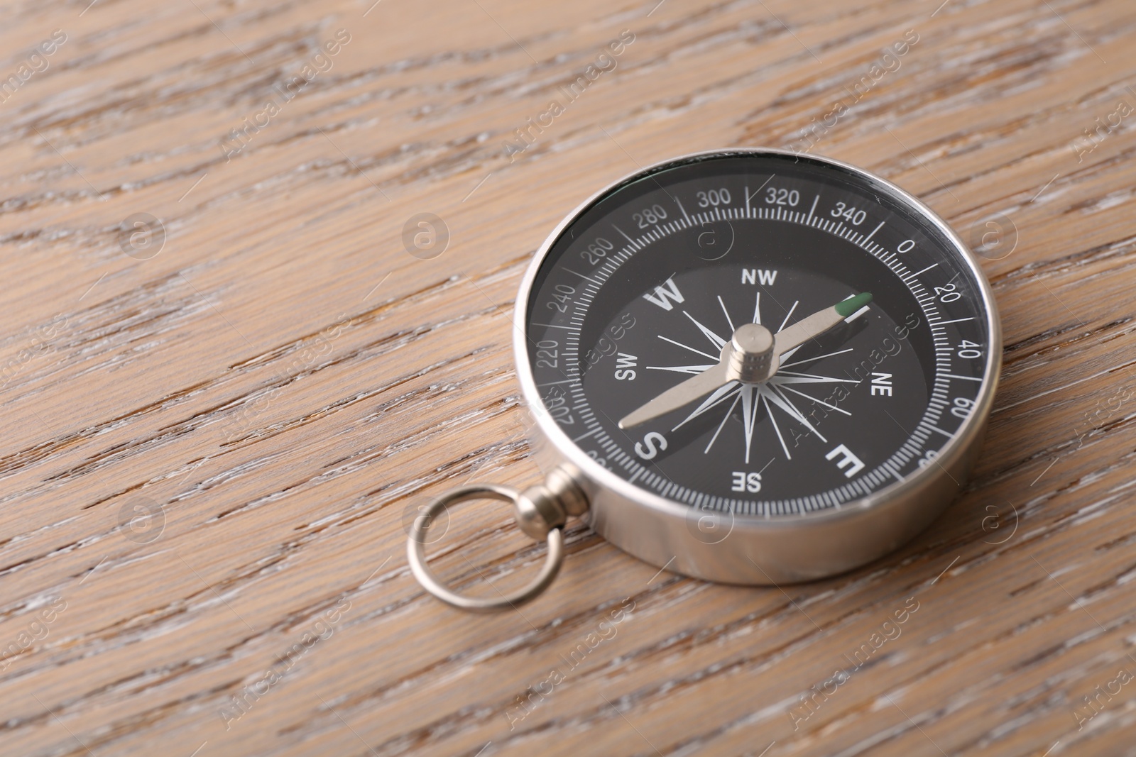 Photo of One compass on wooden table, space for text. Tourist equipment