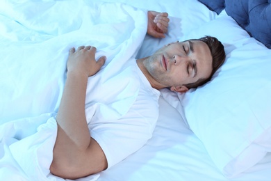 Photo of Young man sleeping in bed at night