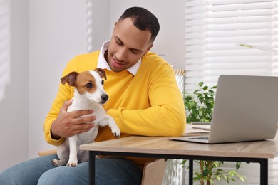 Photo of Young man with Jack Russell Terrier at desk in home office