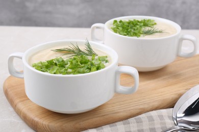 Photo of Bowls with tasty creamy soup of parsnip on light grey table, closeup