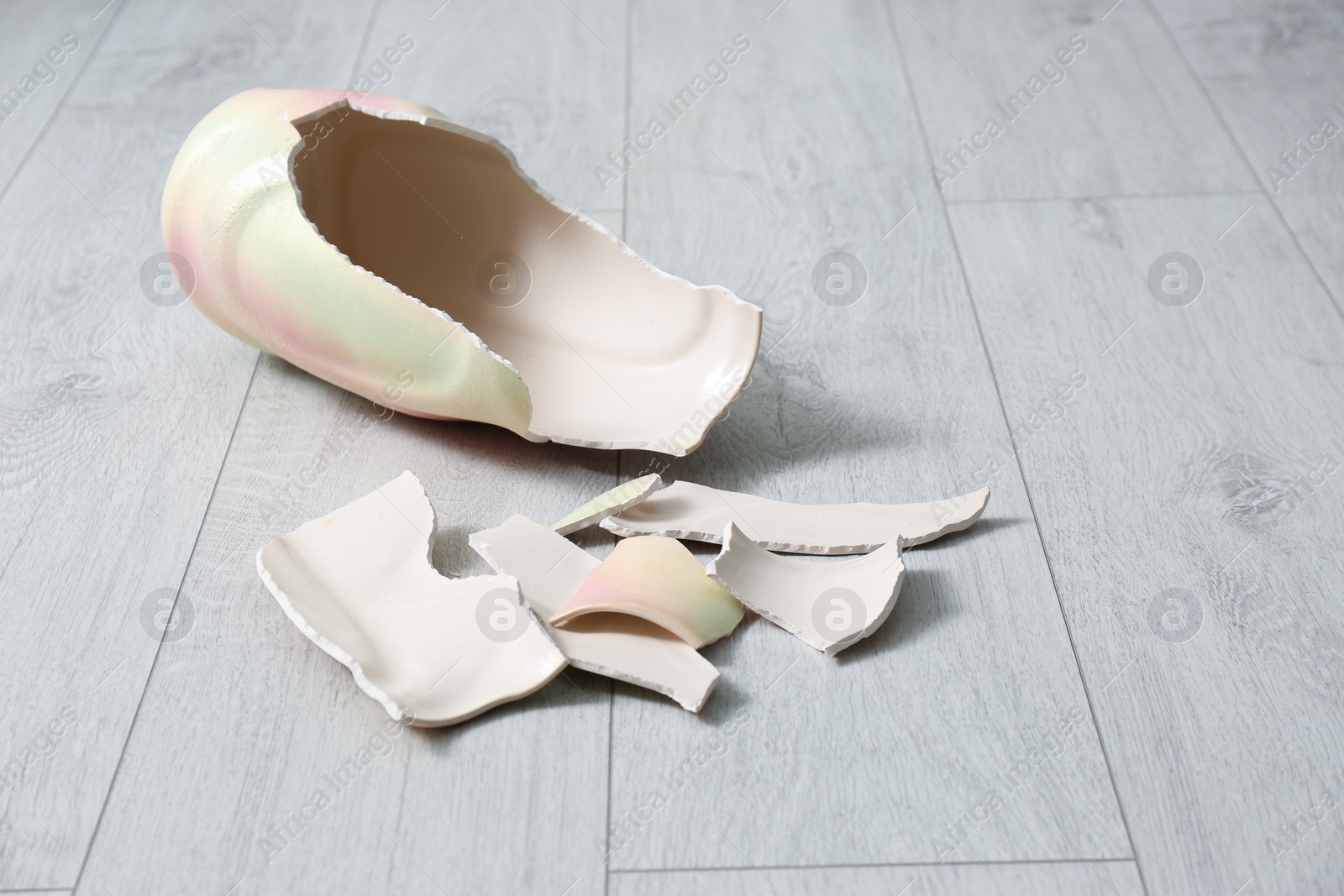 Photo of Broken bright ceramic vase on wooden floor