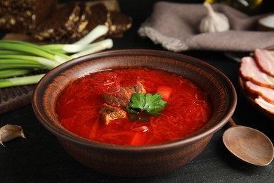 Photo of Stylish brown clay bowl with Ukrainian borsch served on black table